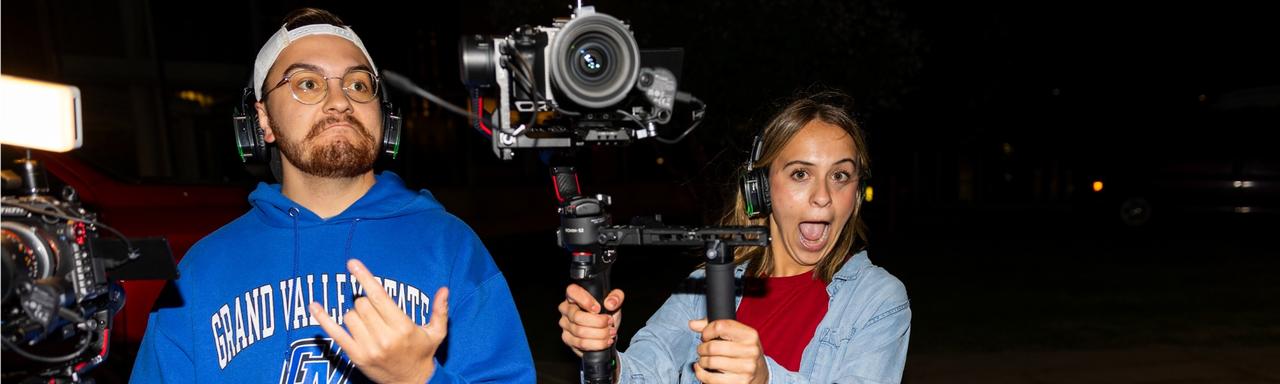 Two students holding cameras and making faces